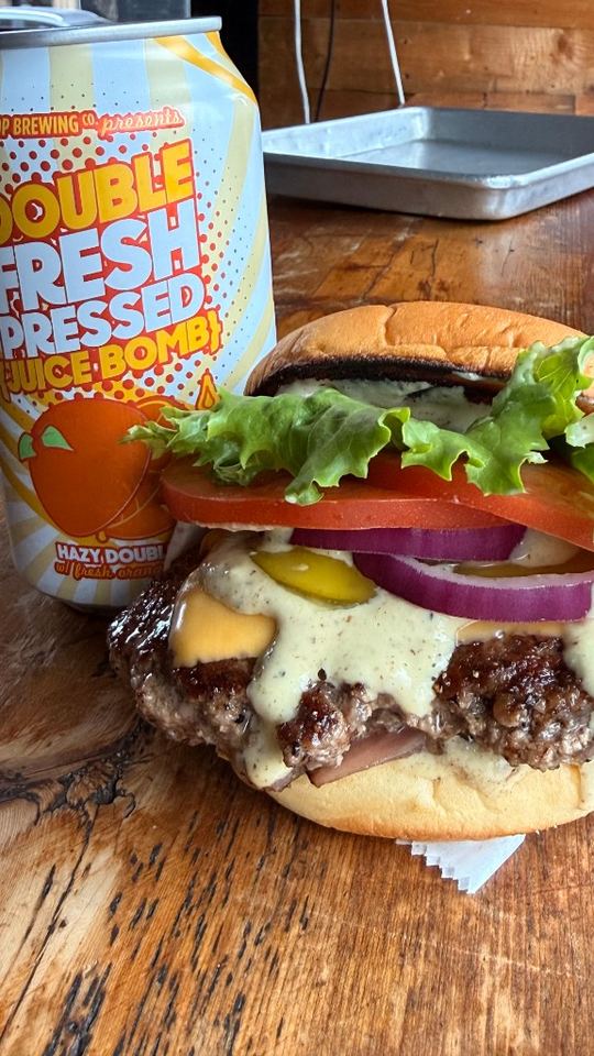 Cheeseburger with craft can pairing on wooden table.