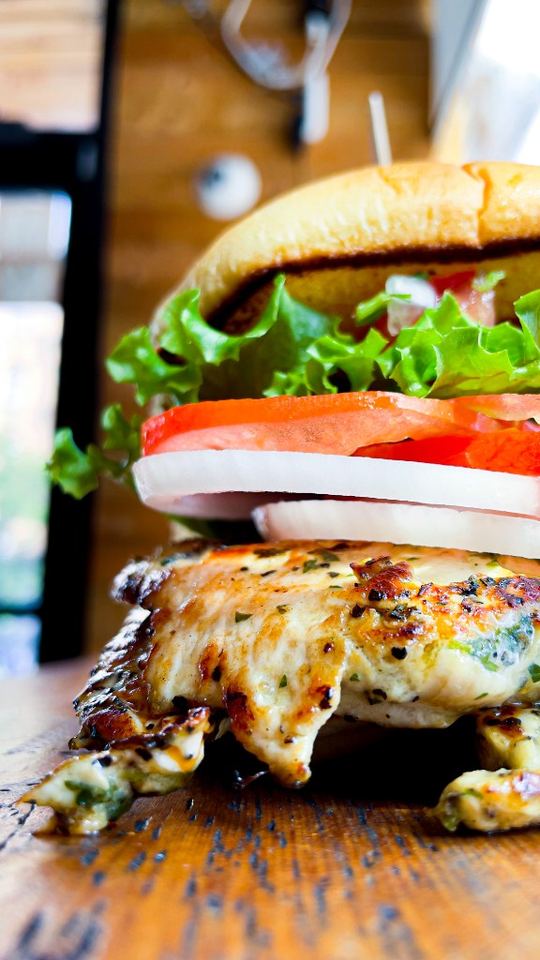 Grilled chicken burger with lettuce, tomato, and onion on a toasted bun.