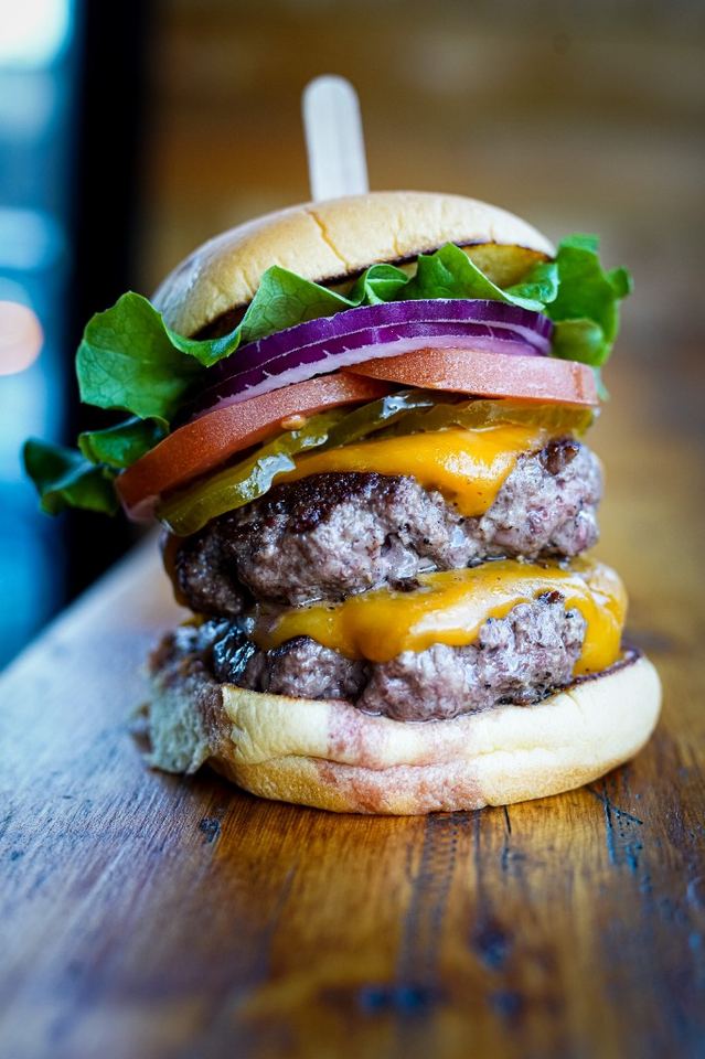 Double smashed cheeseburger with lettuce, tomato, onion, and pickles.