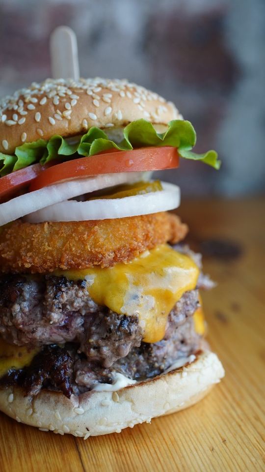 Double cheeseburger stacked with a crispy onion ring and fresh toppings.