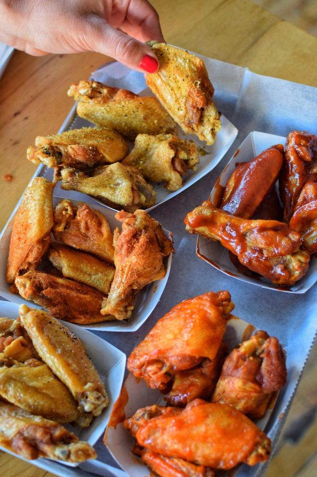Assorted wings with classic and spicy sauces served in trays.