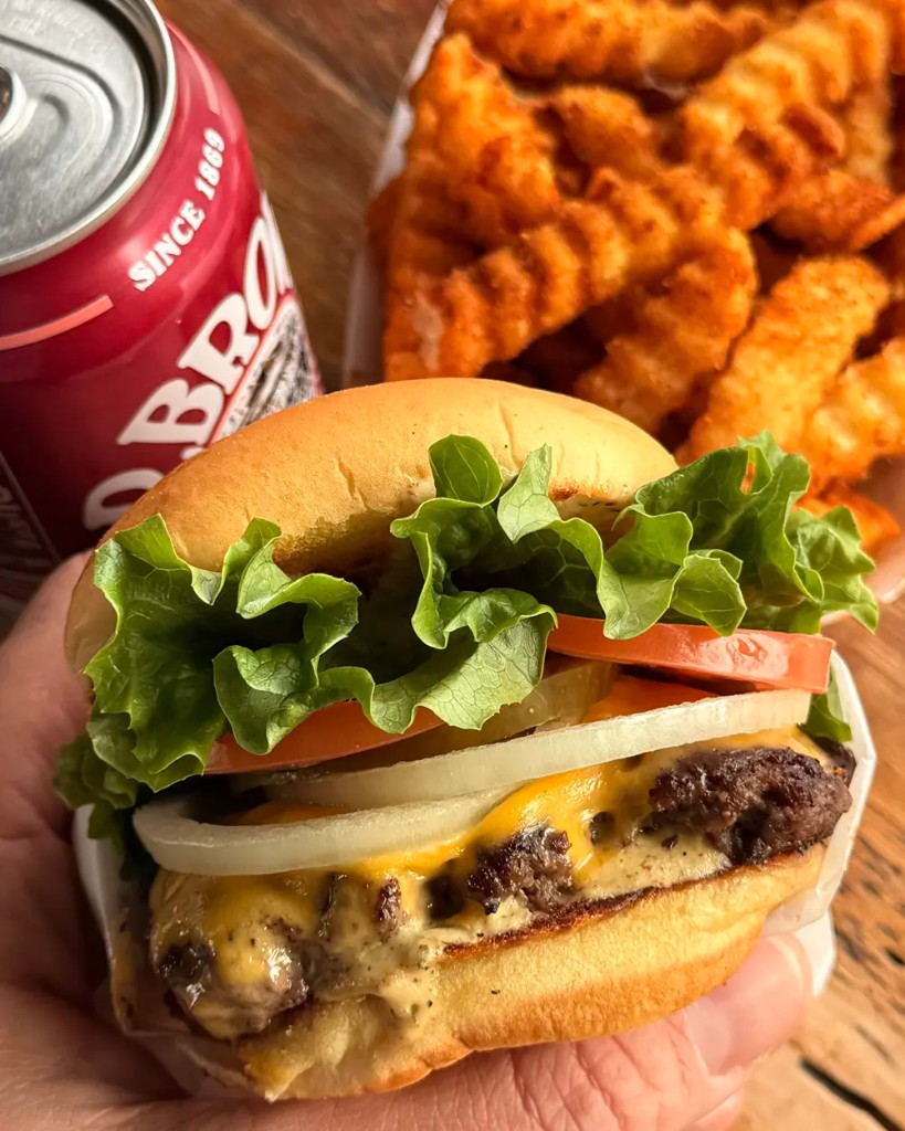 MilkBurger smashed cheeseburger with lettuce, tomato, and onion, served with crinkle-cut fries and an ice-cold D&G Roots soda.